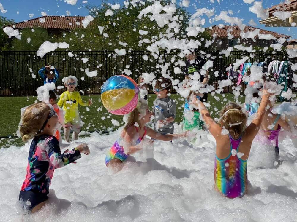 Group playing with beachballs outside in a pile of foam.