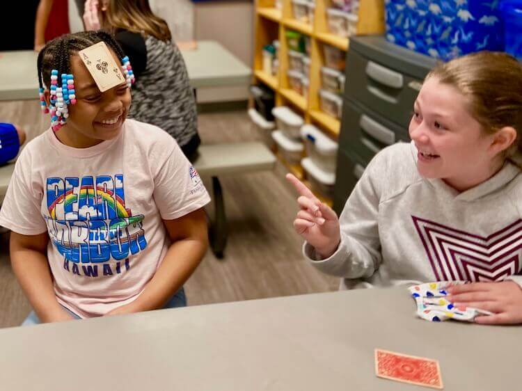 Girls having fun playing with playing cards.