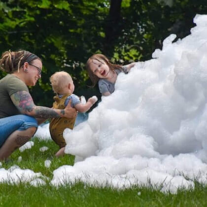 A mom, baby, and toddler playing in a pile of foam.
