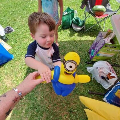 The birthday boy getting a balloon sculpture of a minion.