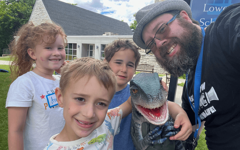 Wayne with kids and a dinosaur.